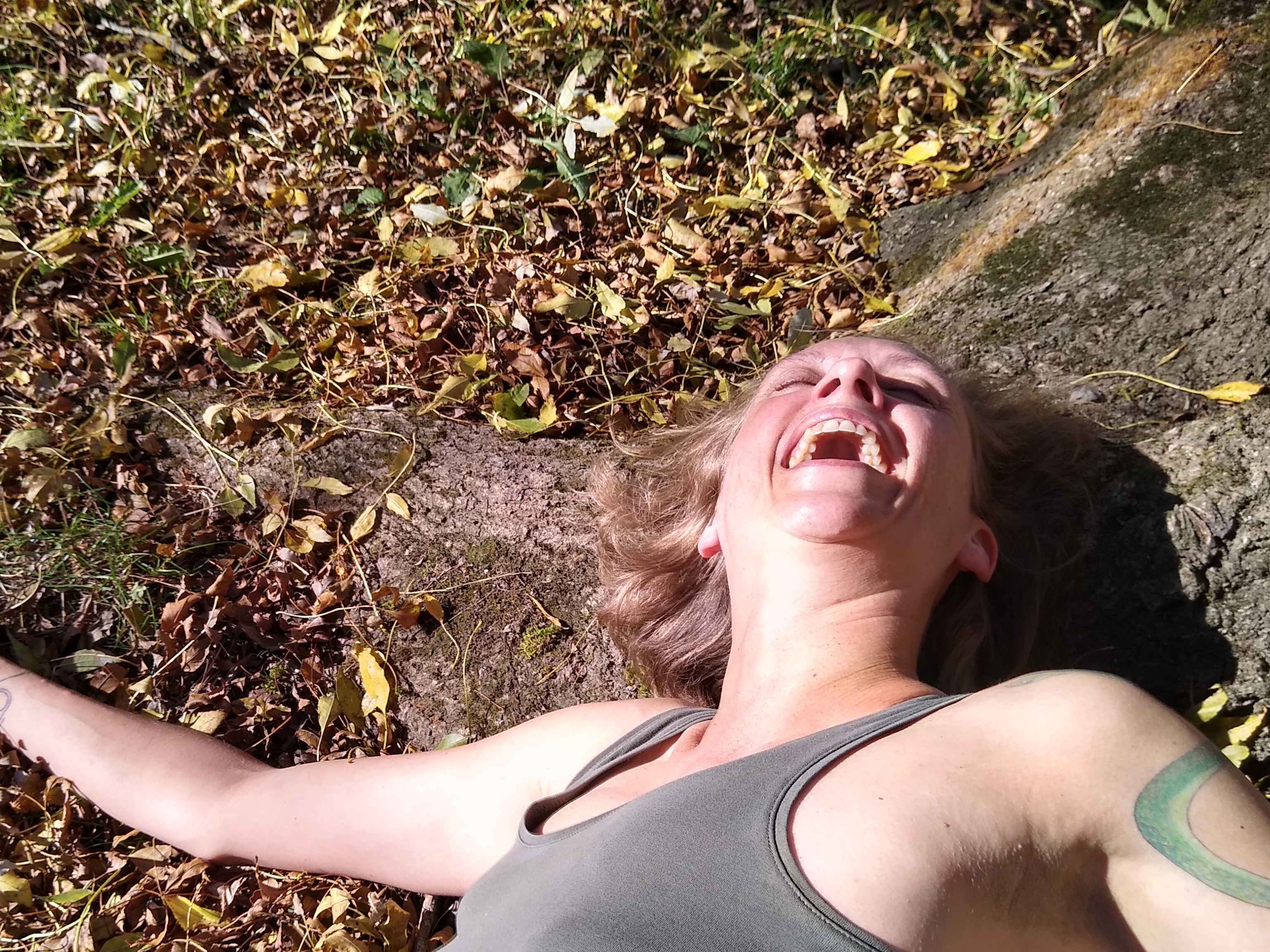 Woman laying at a tree root laughing